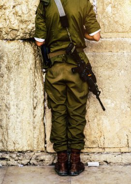 Back of unidentifiable Israeli solder praying on Wailing Western Wall in Jerusalem, Israel. Israel is currently fighting a war against Hamas following terrorist attacks in October 2023 clipart