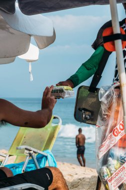 Rio de Janeiro, Brezilya - 25 Aralık 2023: Rio de Janeiro, Brezilya 'daki Leblon Plajı' nda Globo bisküvi satıcısı