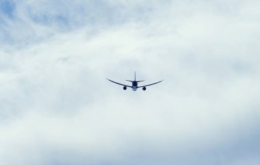 Bir uçak yerden yükseklere süzülüyor, gökyüzündeki kalın bulutları kesiyor. Uçak motorları kabarık beyaz bulutların arasından geçerken kükrüyor.