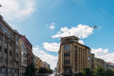 Lisbon, Portugal - April 29, 2024: A bustling street in Lisbon basks under a clear blue sky, flanked by traditional Portuguese buildings with distinctive facades with Fly Tap airplane in background clipart