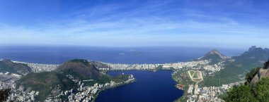 Panoramik bir manzara Rio De Janeiro 'nun doğal ve kentsel güzelliğini gözler önüne seriyor. Bereketli dağların ve geniş Atlantik Okyanusu' nun arka planında ikonik bir gökyüzü var.