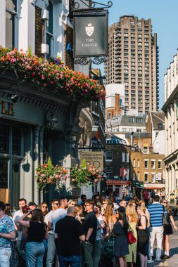 Londra, İngiltere - 30 Haziran 2024: Sıcak bir yaz günü Londra 'da bir barın önünde içen ve dinlenen insanlar