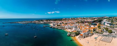 Cascais, parlak mavi gökyüzünün altında kıyı şeridini, altın kumları ve parlak mavi suları kaplayan renkli binalarla çarpıcı bir kıyı manzarası sunuyor, keşif ve rahatlamaya davet ediyor.