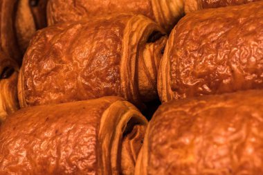 Sıcak, altın kruvasanlar birbirine yakın bir şekilde istiflenir, yumuşak sabah ışığı altında parıldayan yumuşak katmanları, havayı zengin, tereyağlı bir aromayla doldurur.