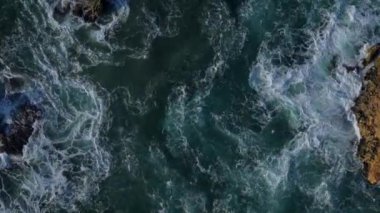 Güneş batarken dalgalar engebeli kayalık oluşumlara şiddetle çarparak çalkantılı sularda ılık tonlar oluşturur. Portekiz, Nazare 'de yakalandı.