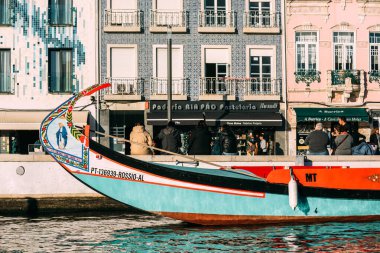 Aveiro, Portugal - December 14, 2024: Colorful traditional boat docked in Aveiro, Portugal with vibrant architecture in the background clipart