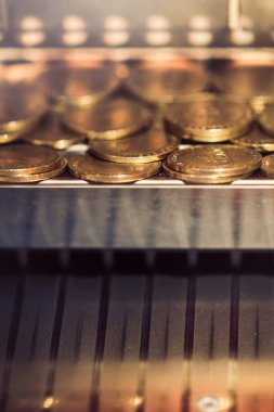 Yığılmış altın paralar, karmaşık metalik detayları vurgulayan bir otomatta dinleniyor.