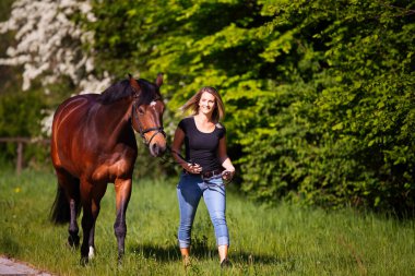 Genç bir kadın atıyla yürüyüşe çıkar. Hitergrund 'da bahar aylarında güneş parlıyor. Diken çiçek açıyor. Metin için alanı olan manzara biçimi.