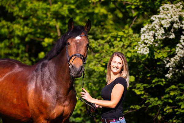 Siyah gömlekli, kısa çizgili esmer saçlı, gün ışığında atının yanında portresi olan genç bir kadın. Kadında keskinlik seviyesi var. Görüntü biçimi bulanık arkaplan ile renklidir.