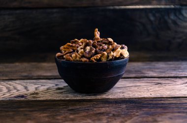 Peeled walnuts in an earthenware dish on a kitchen wooden table