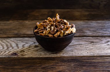 Peeled walnuts in an earthenware dish on a kitchen wooden table