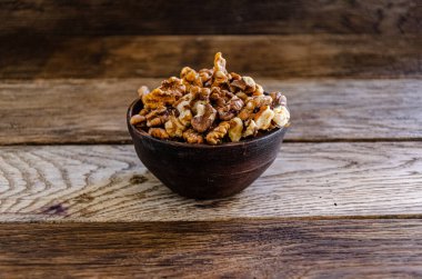 Peeled walnuts in an earthenware dish on a kitchen wooden table