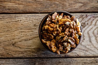 Peeled walnuts in an earthenware dish on a kitchen wooden table