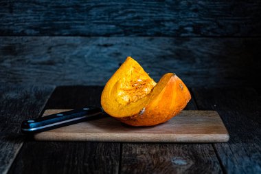 Sliced pumpkin in a white bowl on a wooden table.