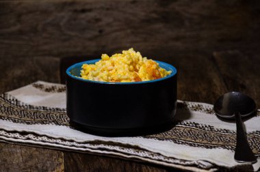 Rice porridge with pumpkin and milk in a ceramic bowl on the kitchen table.