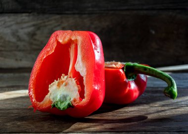 Red bell pepper lies sliced on a cutting board and a knife on the kitchen table. Cooking at home.