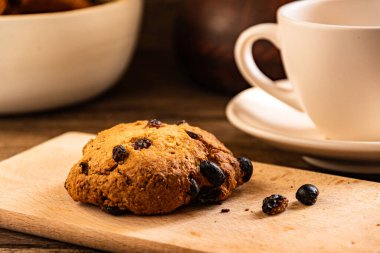 A cup of coffee and oatmeal cookies on the kitchen table.