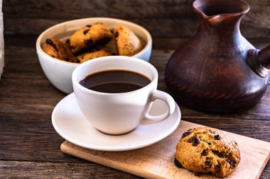 A cup of coffee and oatmeal cookies on the kitchen table.