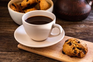 A cup of coffee and oatmeal cookies on the kitchen table.