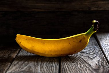 Koyu ahşap zemin üzerinde olgun sarı muz. Mutfakta ev yemeği..