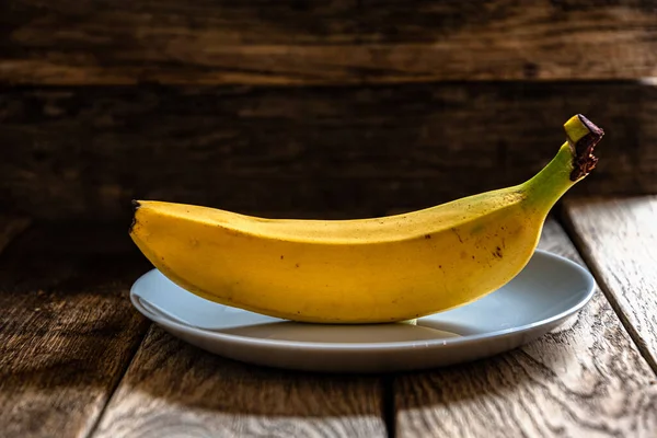 濃い木製の背景に灰色の青いプレートの上に黄色のバナナを熟す キッチンでの家庭料理 — ストック写真