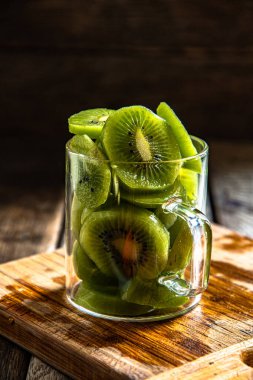 Dilimlenmiş olgun, cam bardakta nefis kivi meyvesi, ahşap bir tahtanın üzerinde, mutfakta arka plan..