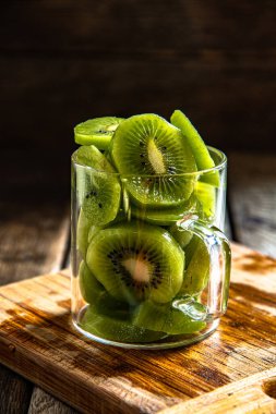 Dilimlenmiş olgun, cam bardakta nefis kivi meyvesi, ahşap bir tahtanın üzerinde, mutfakta arka plan..