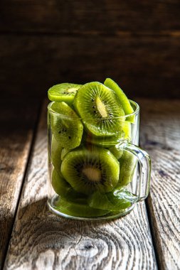 Dilimlenmiş olgun, cam bardakta nefis kivi meyvesi, ahşap bir tahtanın üzerinde, mutfakta arka plan..