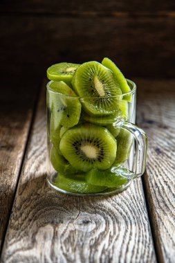 Dilimlenmiş olgun, cam bardakta nefis kivi meyvesi, ahşap bir tahtanın üzerinde, mutfakta arka plan..