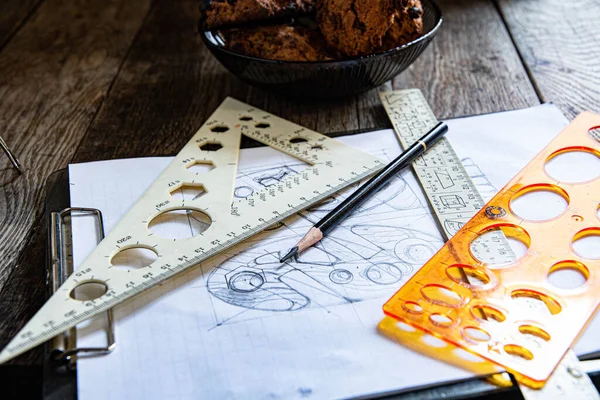 Pencil sketch, rulers, square, and pencil on a wooden table. Attributes of an old designer.
