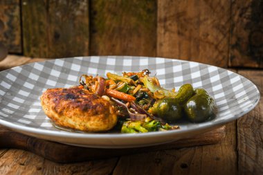 Üstünde et ve sebze olan bir tabak yemek. Tabak ahşap bir masanın üzerinde.