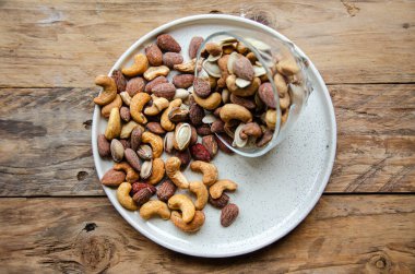 Ahşap mutfak masasında cam bir kasede çeşitli fındıklar..