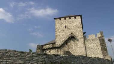 Ortaçağ taş kulesinin üzerinde mavi bir gökyüzünde hareket eden bulutlar.