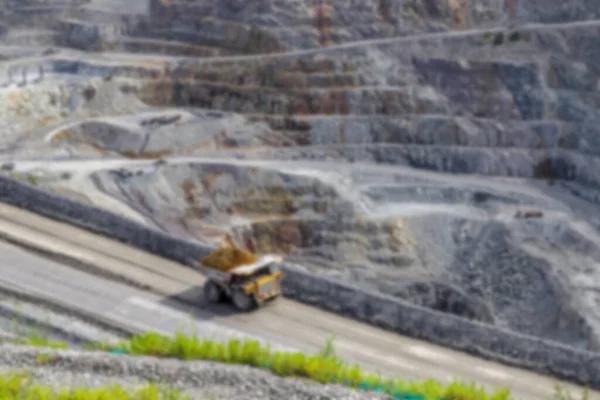 Blurred background of dump truck hauling ore at open pit mining site