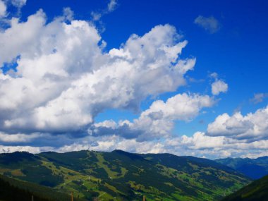 Bir yaz günü Saalbach Hinterglemm kayak merkezi yakınlarındaki dağlarda yeşil çayırlar, dağlar, bulutlar. Alpler, Avusturya. 
