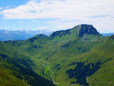 Bir yaz günü Saalbach Hinterglemm kayak merkezi yakınlarındaki dağlara, yeşil çayırlara, dağlara, mavi gökyüzüne, bulutlara, arka planda buzullarla Hohen Tauern dağlarına bakın. Alpler, Avusturya. 
