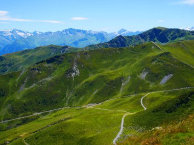 Bir yaz günü Saalbach Hinterglemm kayak merkezi yakınlarındaki dağlara, yeşil çayırlara, dağlara, mavi gökyüzüne, bulutlara, arka planda buzullarla Hohen Tauern dağlarına bakın. Alpler, Avusturya. 
