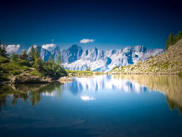 Dağ gölü, dağ tepeleri, taşlar, ağaçlar, mavi gökyüzü olan manzaralı dağ manzarası. Mavi. Schladminger Tauern, Alpler, Avusturya.