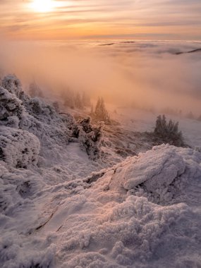 Sıcaklığın tersine dönmesi, kar, gürültü, bulutlar, ladin ağaçları, kayalar boyunca alçak bulutlar ve sisle dolu bir dağ sırasından vadiye manzara. Jeseniky Dağları. Çek Cumhuriyeti.