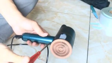  Adam saç kurutma makinesini tamir ediyor.