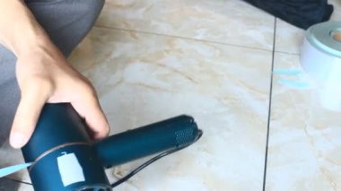  Adam saç kurutma makinesini tamir ediyor.