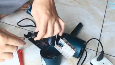  Adam saç kurutma makinesini tamir ediyor.