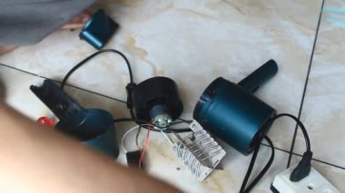  Adam saç kurutma makinesini tamir ediyor.