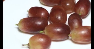 Tabakta üzüm var. Beyaz bir tabakta bir demet mor üzüm. Beyaz tabak dönüyor.