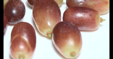 Tabakta üzüm var. Beyaz bir tabakta bir demet mor üzüm. Beyaz tabak dönüyor.