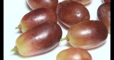 Tabakta üzüm var. Beyaz bir tabakta bir demet mor üzüm. Beyaz tabak dönüyor.