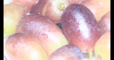 Tabakta üzüm var. Beyaz bir tabakta bir demet mor üzüm. Beyaz tabak dönüyor.