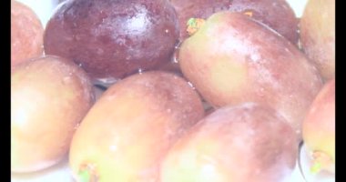 Tabakta üzüm var. Beyaz bir tabakta bir demet mor üzüm. Beyaz tabak dönüyor.