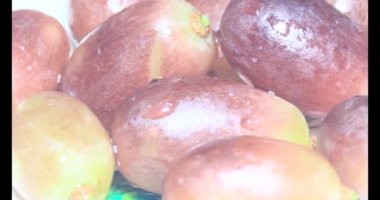 Tabakta üzüm var. Beyaz bir tabakta bir demet mor üzüm. Beyaz tabak dönüyor.