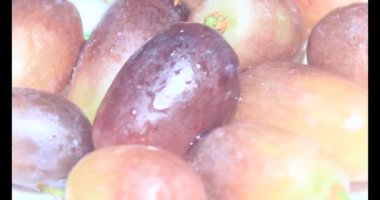 Tabakta üzüm var. Beyaz bir tabakta bir demet mor üzüm. Beyaz tabak dönüyor.